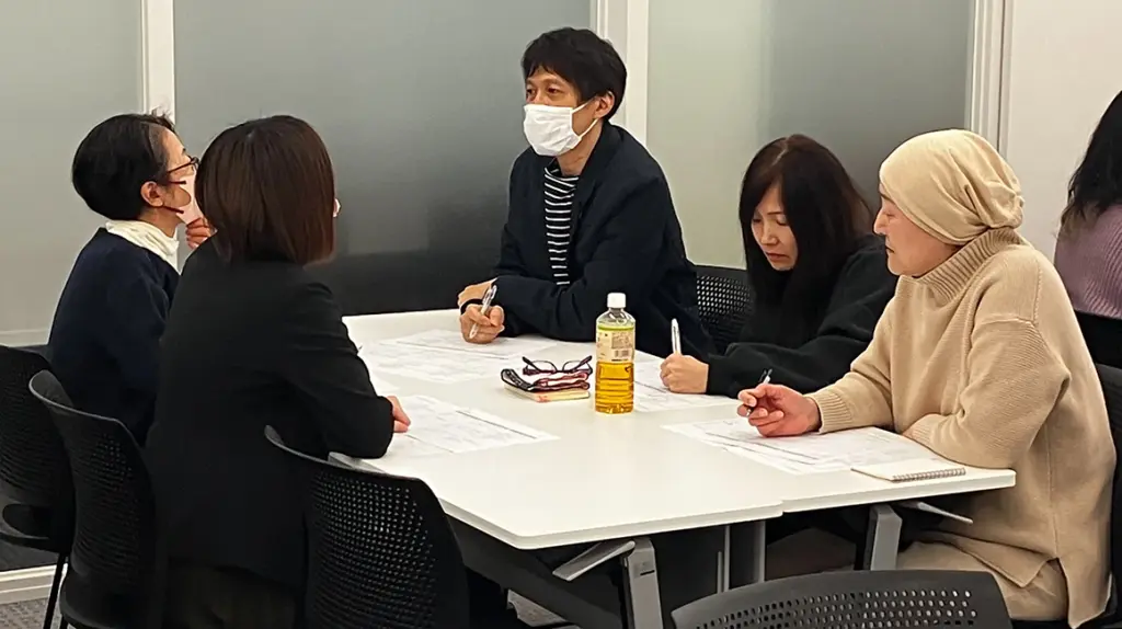 会議室で話し合う5人の男女